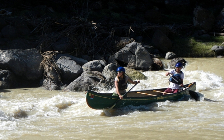 two people navigate whitewater in a canoe